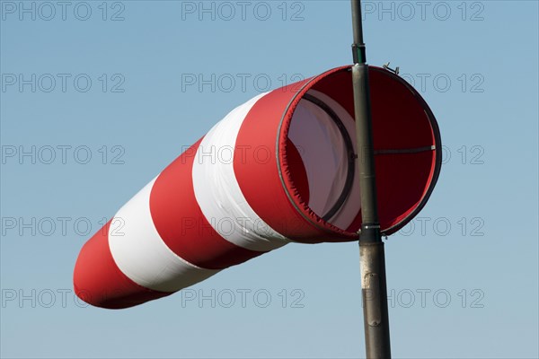 Red and white windsock against a blue sky