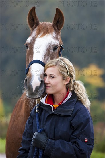 Young woman cuddling a Austrian Warmblood