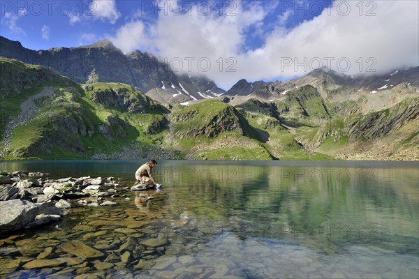 Mountaineer filling a water bottle at Grosser Schwarzsee Lake or Lago Nero