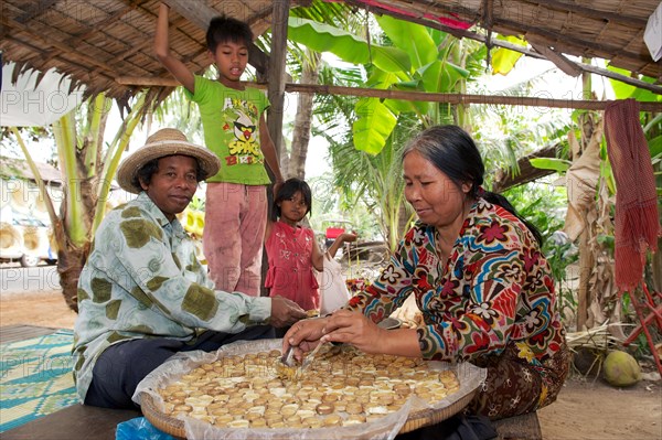 Woman pouring hot palm sugar in forms made of bamboo