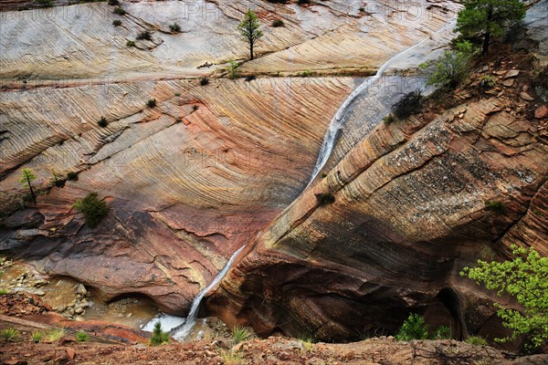 Water draining off over red Navajo sandstone rocks after a rainstorm near Canyon Overlook