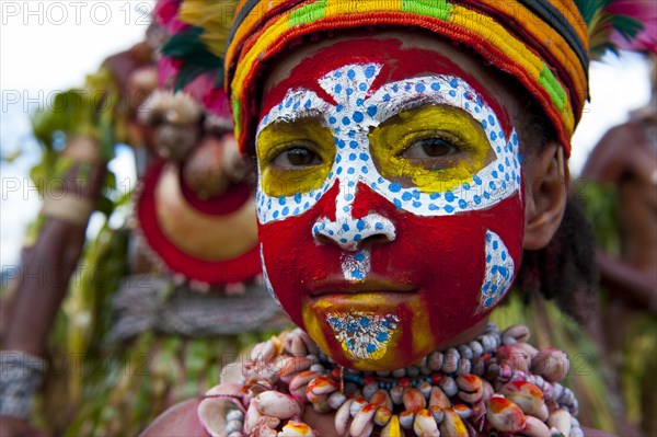 Member of a tribe in a colourfully decorated costume with face paint at the traditional sing-sing gathering