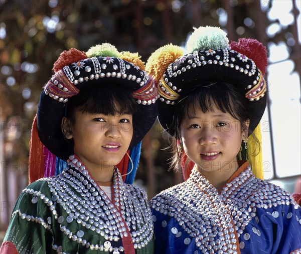 Two Lisu girls wearing colourful headdresses and the traditional costume of the mountain people