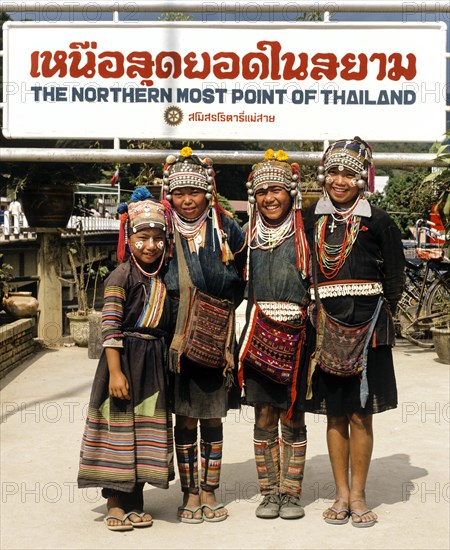 Akha hill tribe girls wearing traditional costumes and headdresses standing at the northernmost point of Thailand