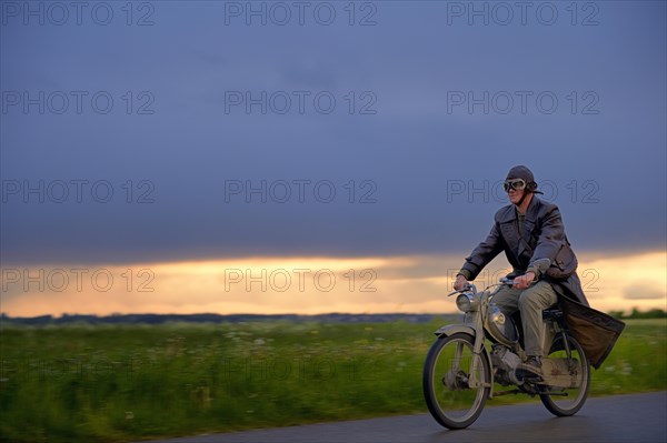 Vintage motorcyclist in front of a dramatic cloudy sky