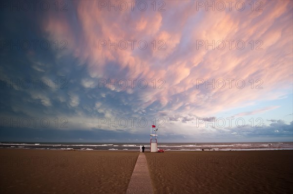 Moody clouds with the afterglow of sunset by the sea with an observation tower