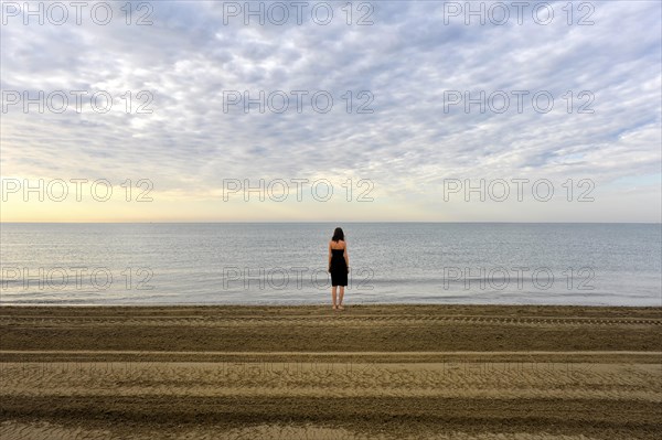 Woman wearing a black dress standing by the sea