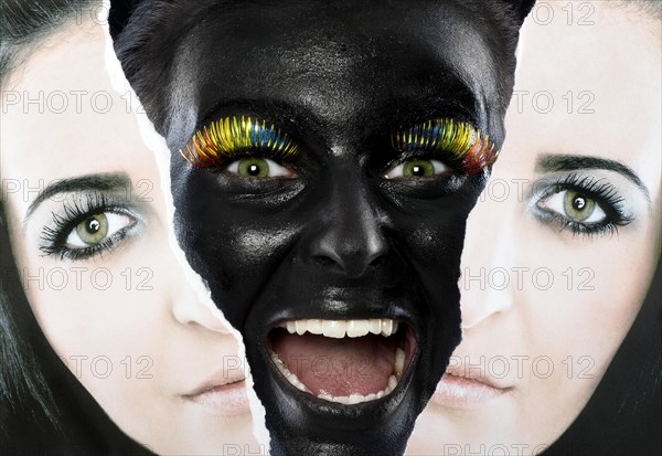 Face of a laughing young woman painted with black facepaint looking through a torn portrait photo