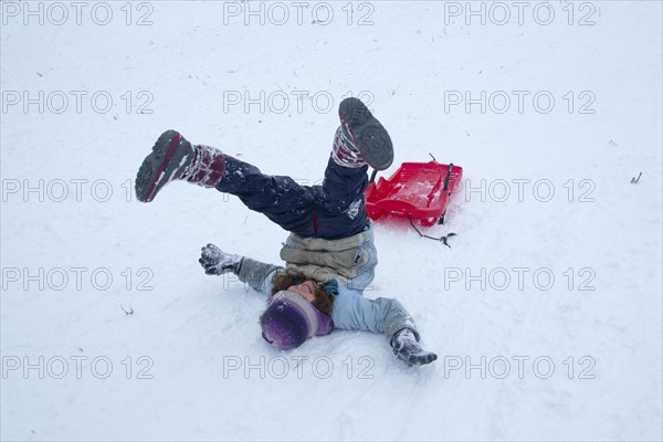 Girls rolling in the snow while sledding