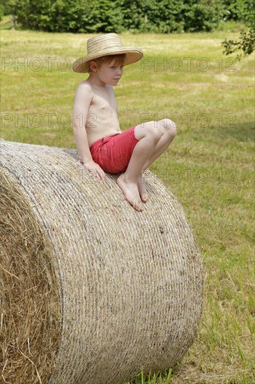 Boy sitting on a bale of straw