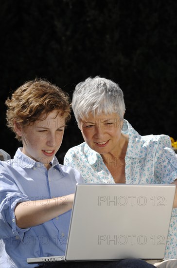 Grandson is showing his grandmother something on a laptop computer