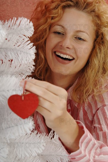 Woman is decorating a white Christmas tree