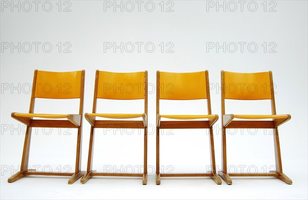 Four old orange school chairs standing side by side