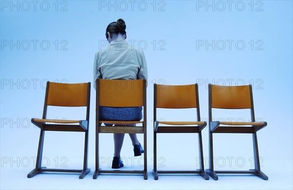 Woman wearing conservative clothes sitting on one of four orange chairs