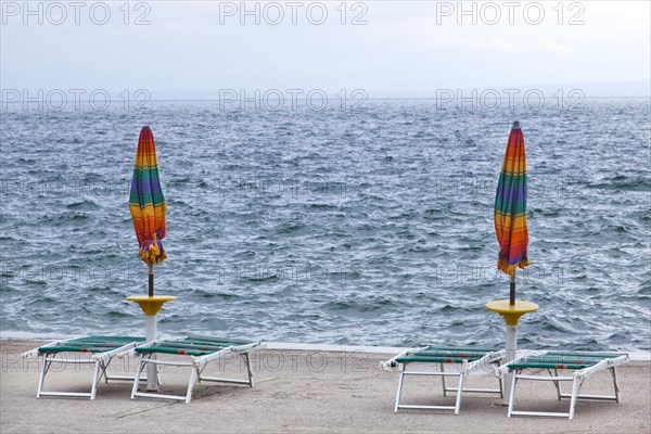 Umbrellas and deckchairs during the preseason on the beach of Opatija on the Mediterranean Sea in Kvarner Bay