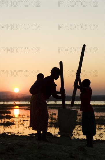 Tongan women in pounding grain on the shore of Lake Kariba