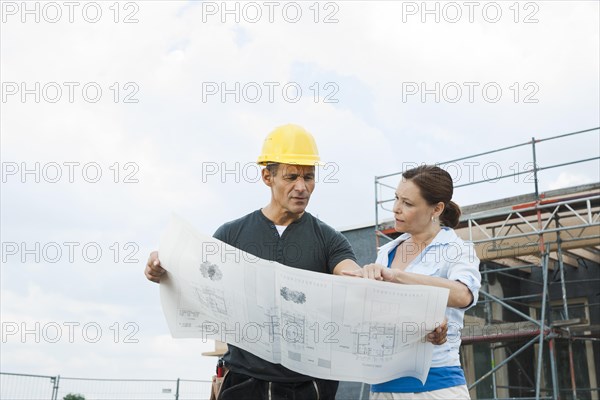 Construction manager and building owner discussing plans on a construction site