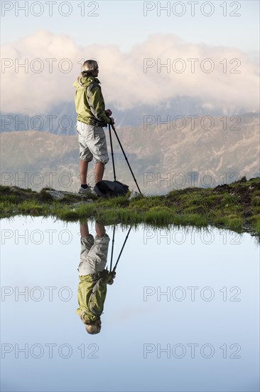 Reflection of a female hiker small lake looking at the Kalkkoegel range