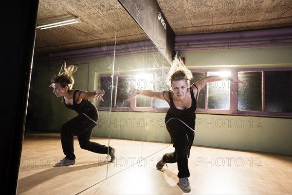 Breakdancer dancing in front of a mirror wall