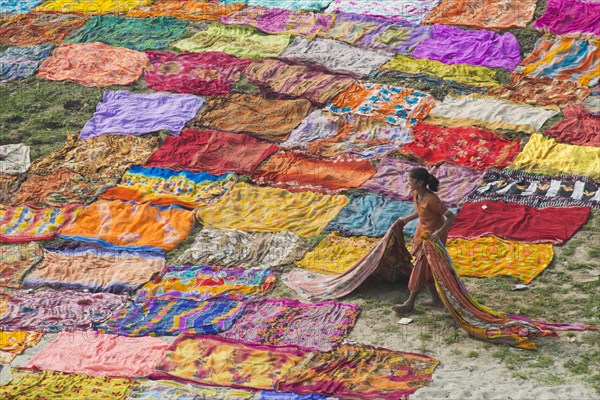 Colourful saris laying to dry after washing on a sandbank on the banks of the Yamuna River