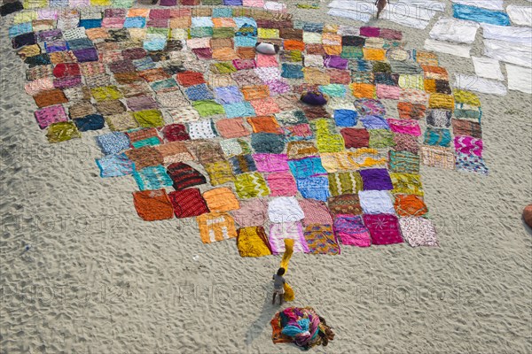 Colourful saris laying to dry after washing on a sandbank on the banks of the Yamuna River