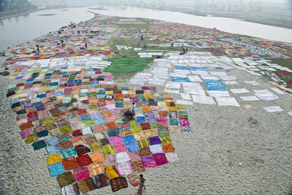 Colourful saris laying to dry after washing on a sandbank on the banks of the Yamuna River