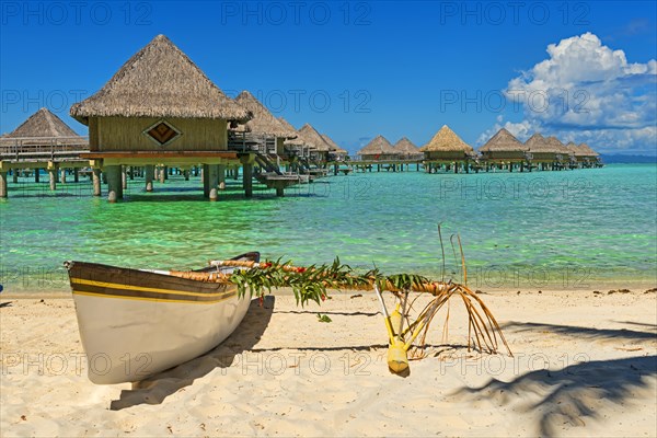 Polynesian outrigger canoe in front of pile bungalow complex