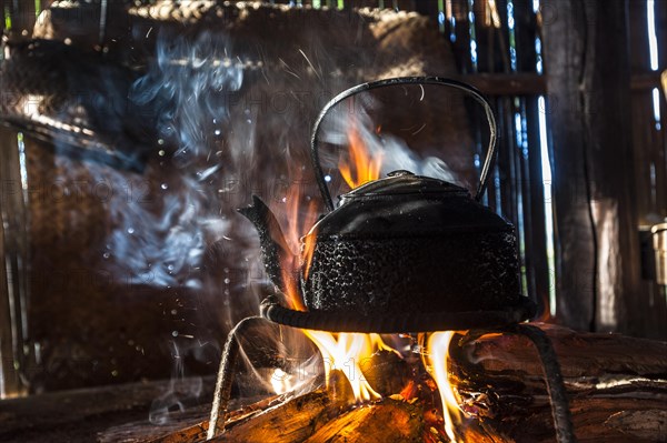 Kettle over an open fire in a kitchen made of bamboo