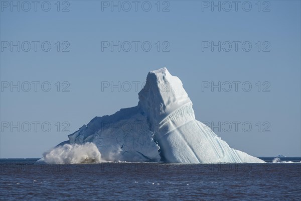 Pieces breaking off an enormous iceberg causing it to unbalance and collapse