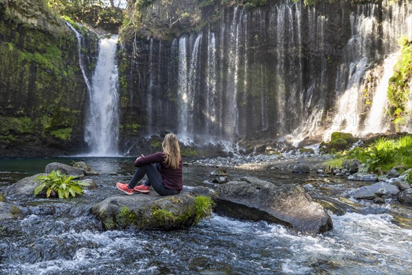 Young woman sitting on a stone in a river