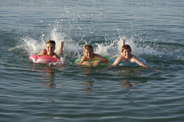 Children on floating tyres in the sea