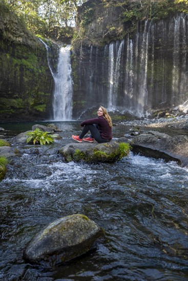 Young woman sitting on a stone in a river