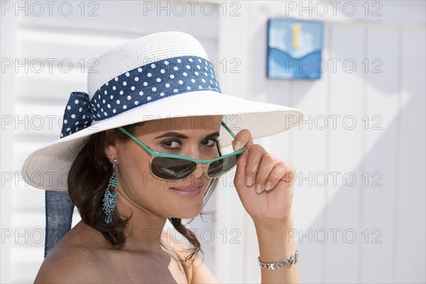 Woman with hat looking over the rim of her sunglasses