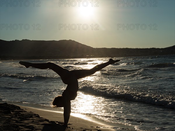 Young woman doing gymnastics on the beach