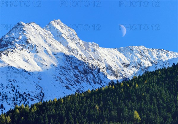 Half moon over snowy peaks