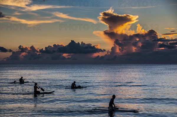 Surfers at sunset in Guam