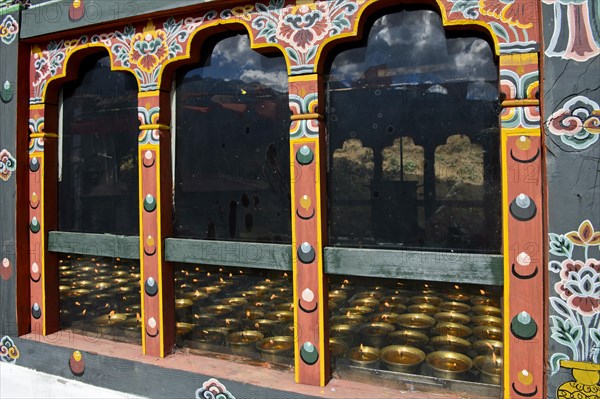 Lit butter lamps seen through a window