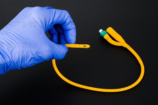 A hand with a blue medical glove is holding a balloon catheter