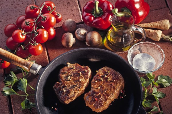 Two fried pepper steaks in a pan