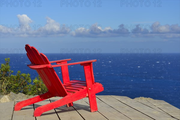 Red wooden chair on a terrace overlooking the Mediterranean Sea