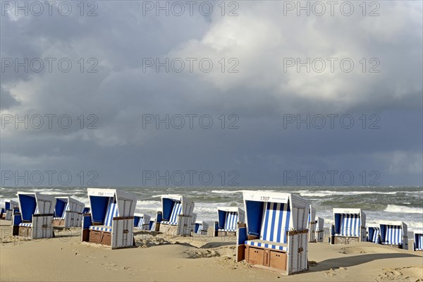 Beach of Westerland with white-blue beach chairs and rain clouds