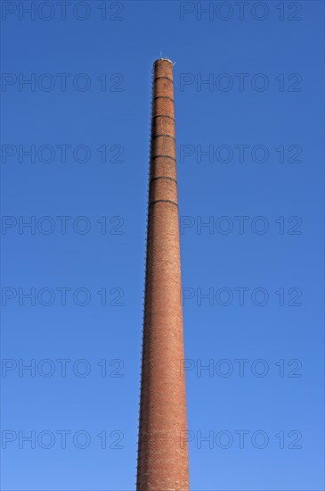 Old brick factory chimney against blue sky