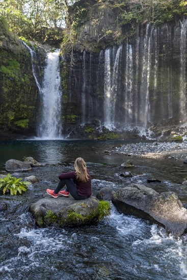 Young woman sitting on a stone in a river