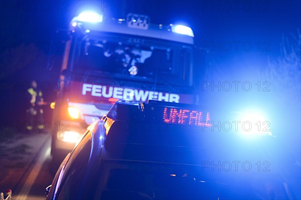 Fire engine and police car with flashing blue lights and the LED display 'Unfall'