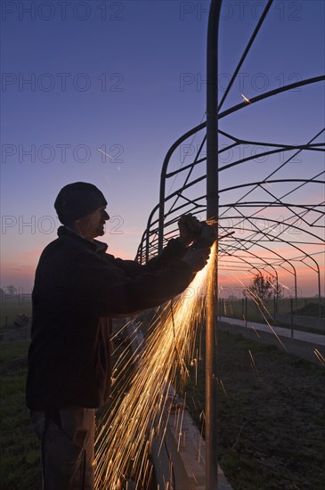 Young man grinding on a metal frame at dusk