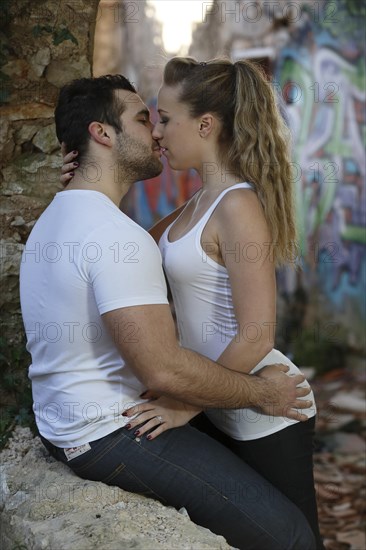 Young couple kissing in a ruined building covered in graffiti