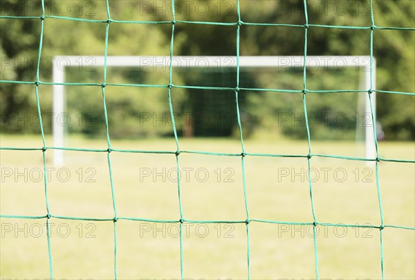 Empty soccer field seen through the net of the goal