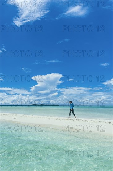 Tourist walking on a sand strip at low tide