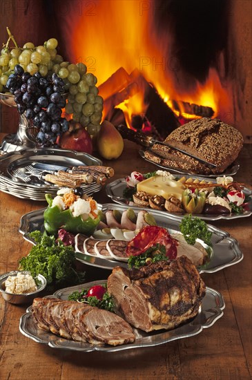 Cold Franconian buffet decorated on pewter in front of a burning fireplace