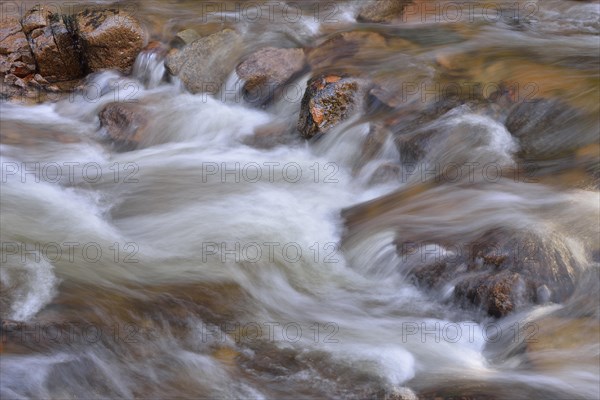 Water running over rocks in a brook in autumn